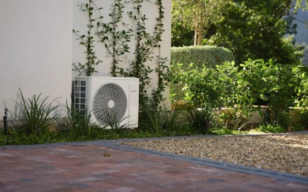 Außeneinheit einer Split-Klimaanlage von Vaillant, fachgerecht am Haus installiert im Garten