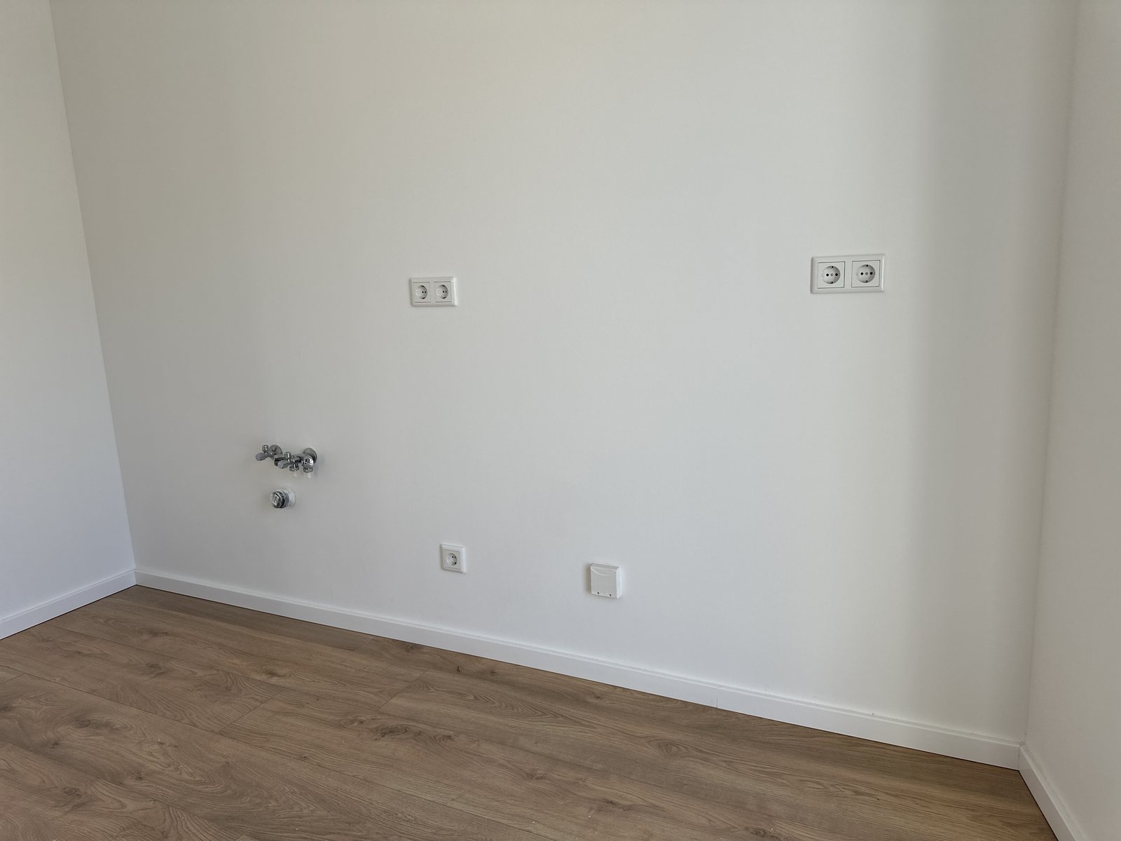 Fertig installierte Anschlusswand einer Wohnung mit Doppelsteckdosen, Sanitäranschlüssen sowie Netzwerk- und Antennendose