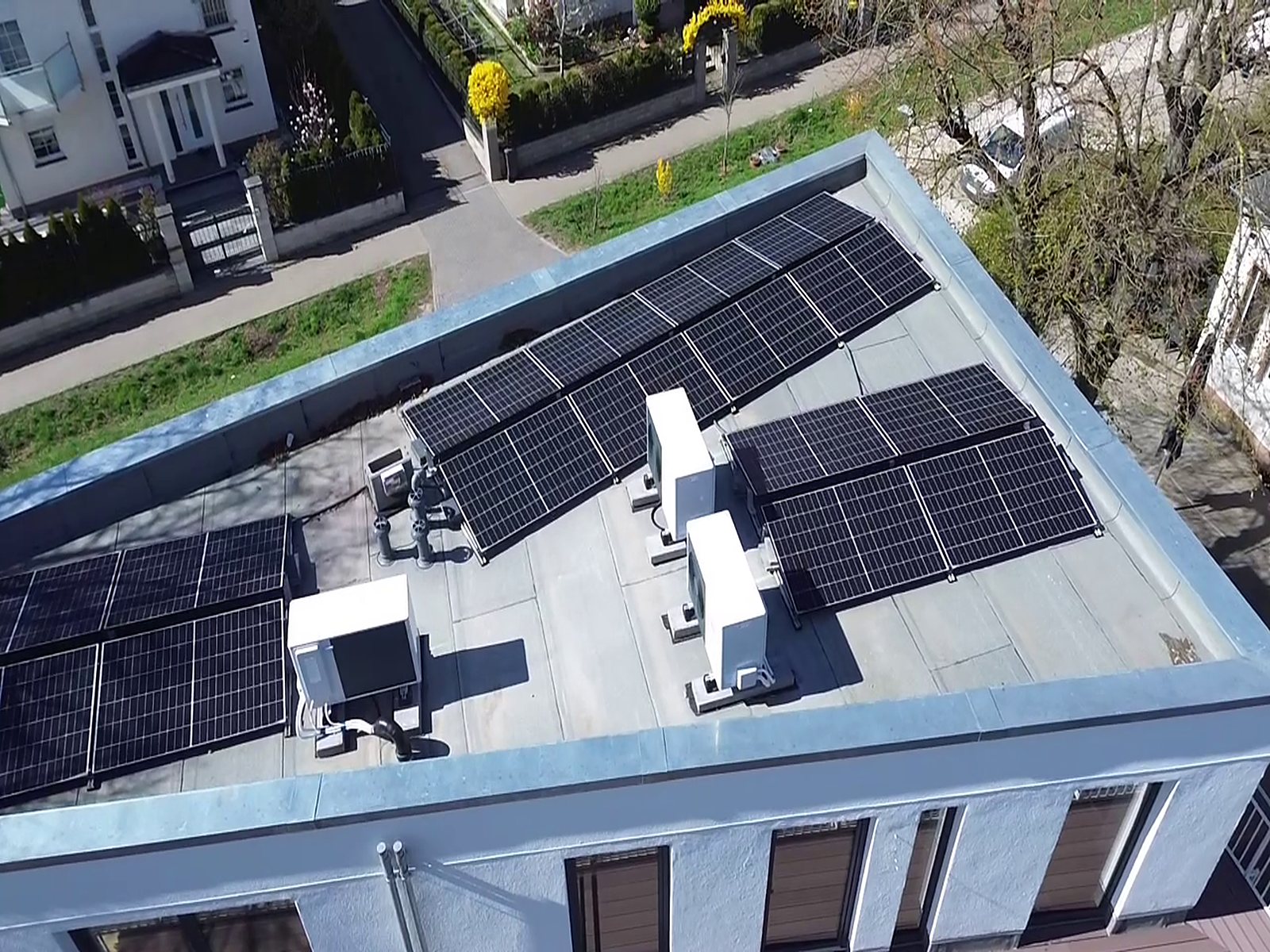 Flachdach eines Mehrfamilienhauses in Berlin aus der Luft: Photovoltaikmodule, zwei Wärmepumpen-Außeneinheiten und Technikaufbauten