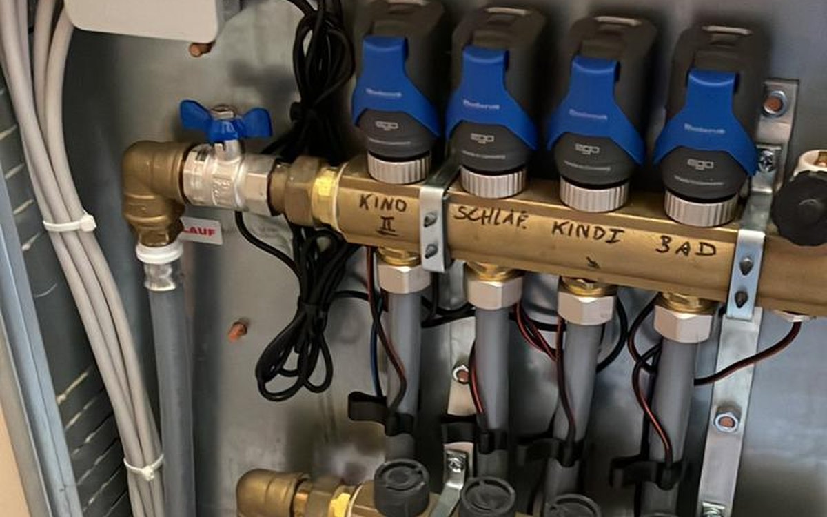Heizkreisverteiler einer Fußbodenheizung mit Stellantrieben, Durchflussmessern und raumweise beschrifteten Heizkreisen nach hydraulischem Abgleich