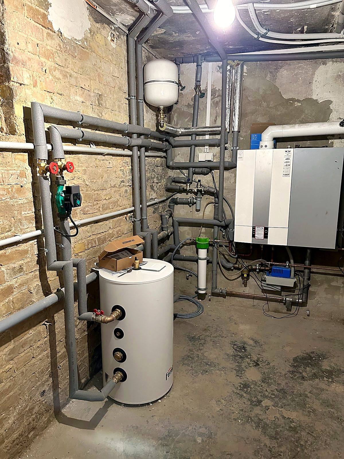 Neu installierte Haustechnik im Keller mit Warmwasserspeicher und übersichtlich verlegten Rohrleitungen