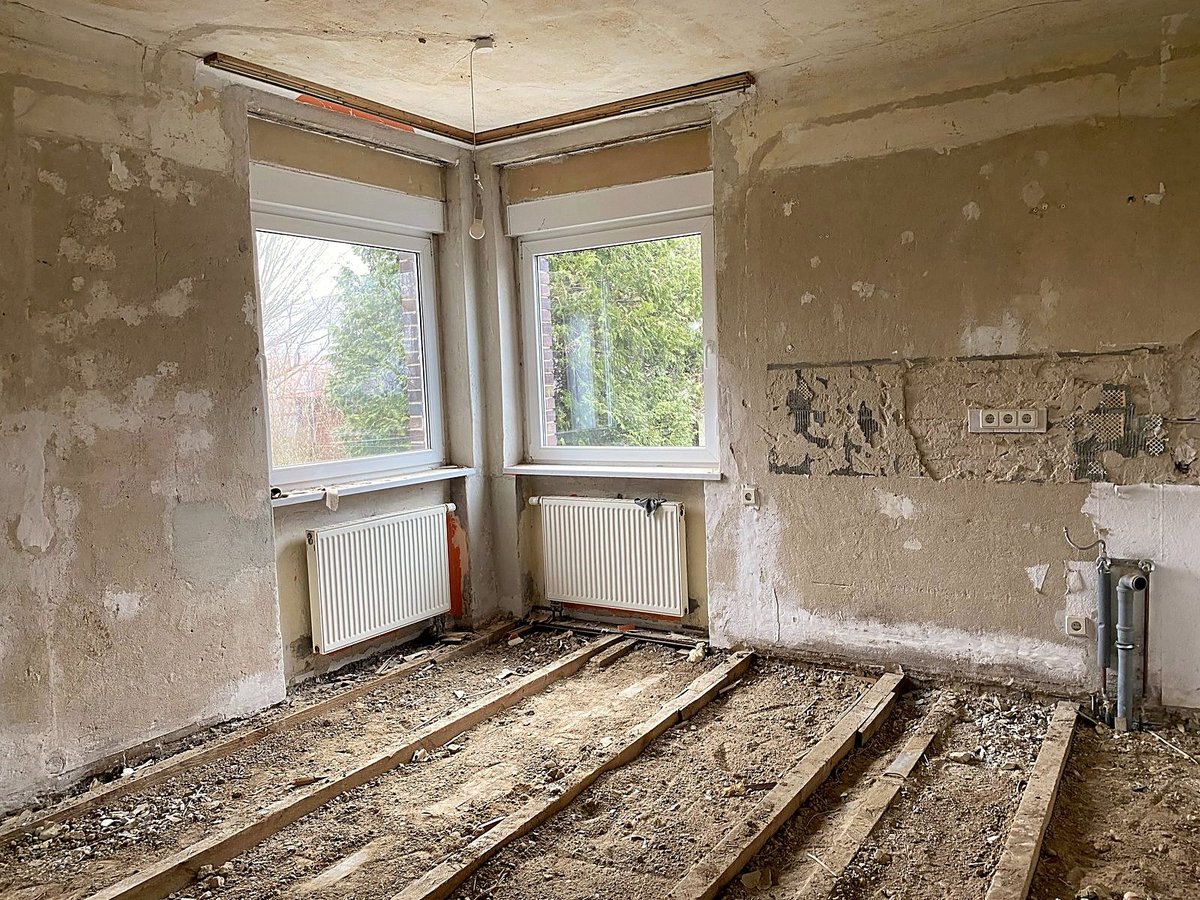 Entkernter Wohnraum mit freigelegter Balkenlage und abgeschlagenem Putz während der Sanierung