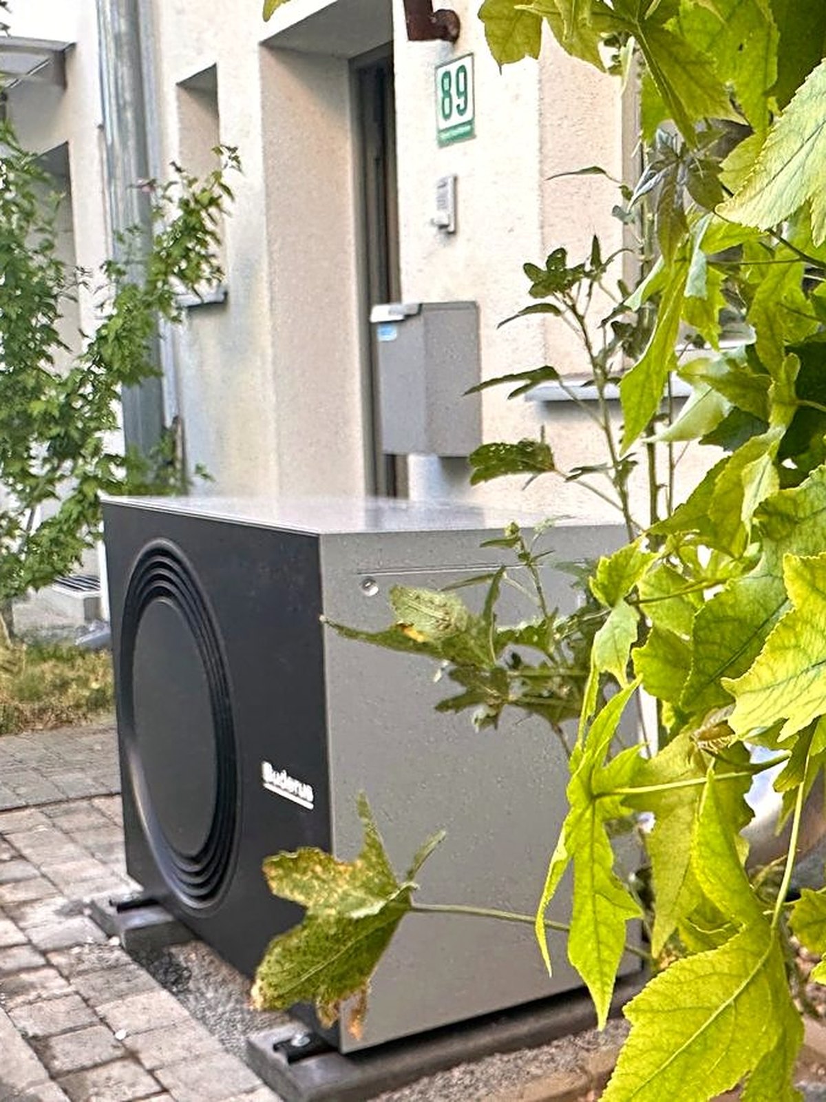 Graue Buderus Wärmepumpe im begrünten Vorgarten eines Einfamilienhauses