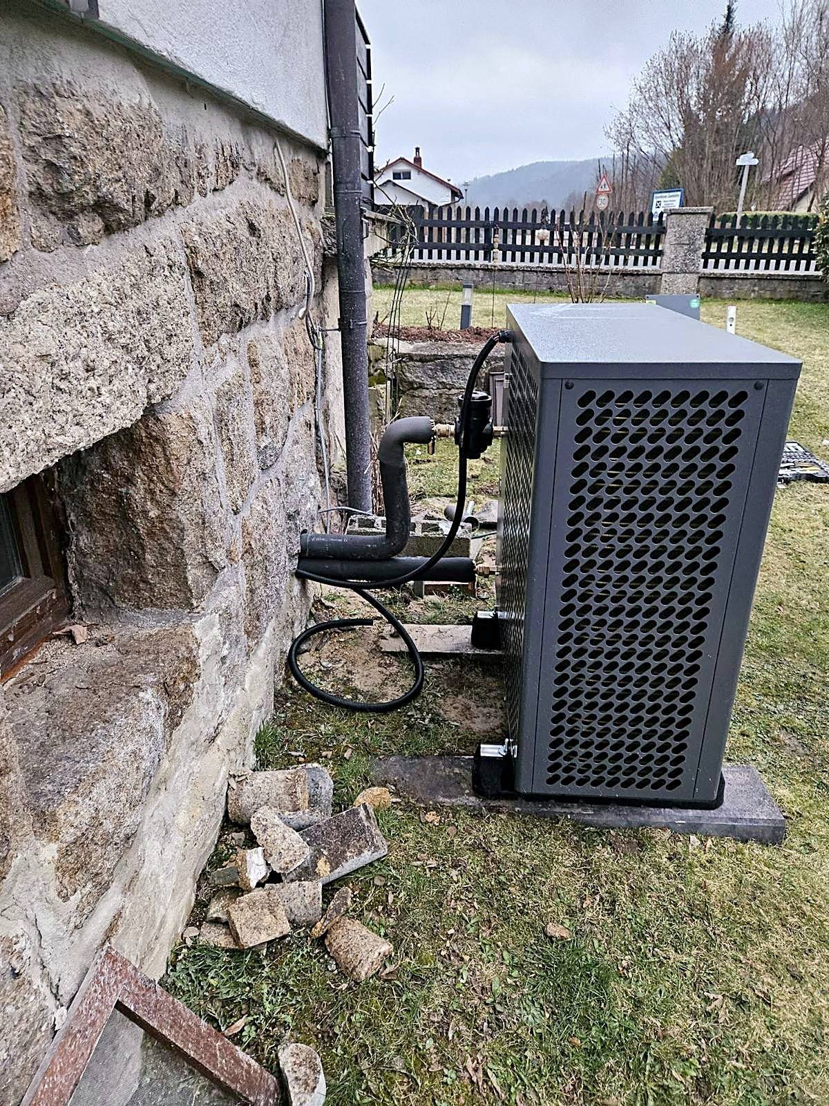 Luft-Wasser-Wärmepumpe an einem Altbau mit Natursteinsockel