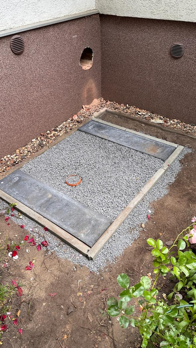 Fertiges Fundament mit Kiesbett neben der Hauswand, Kernbohrung für die Leitungsdurchführung gesetzt