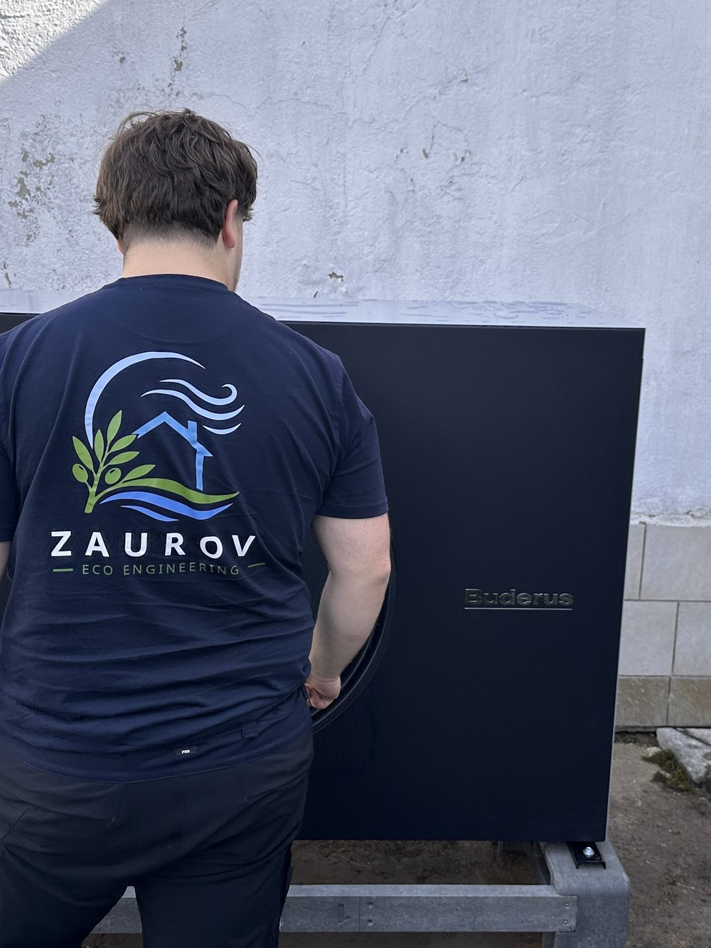 Monteur von Zaurov Eco Engineering bei der Inbetriebnahme einer Buderus Luft-Wärmepumpe auf frisch gesetztem Fundament