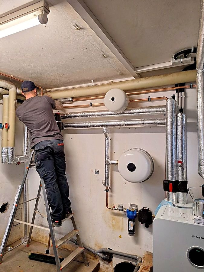 Monteur der Zaurov Eco Engineering bei der Montage der Heizungsleitungen im Technikraum einer Wärmepumpenanlage