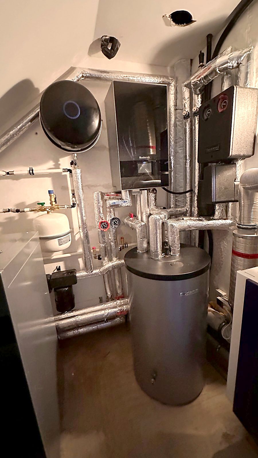 Warmwasserspeicher mit gedämmten Leitungen, Ausdehnungsgefäß und Magnetitabscheider in einem kleinen Heizungsraum