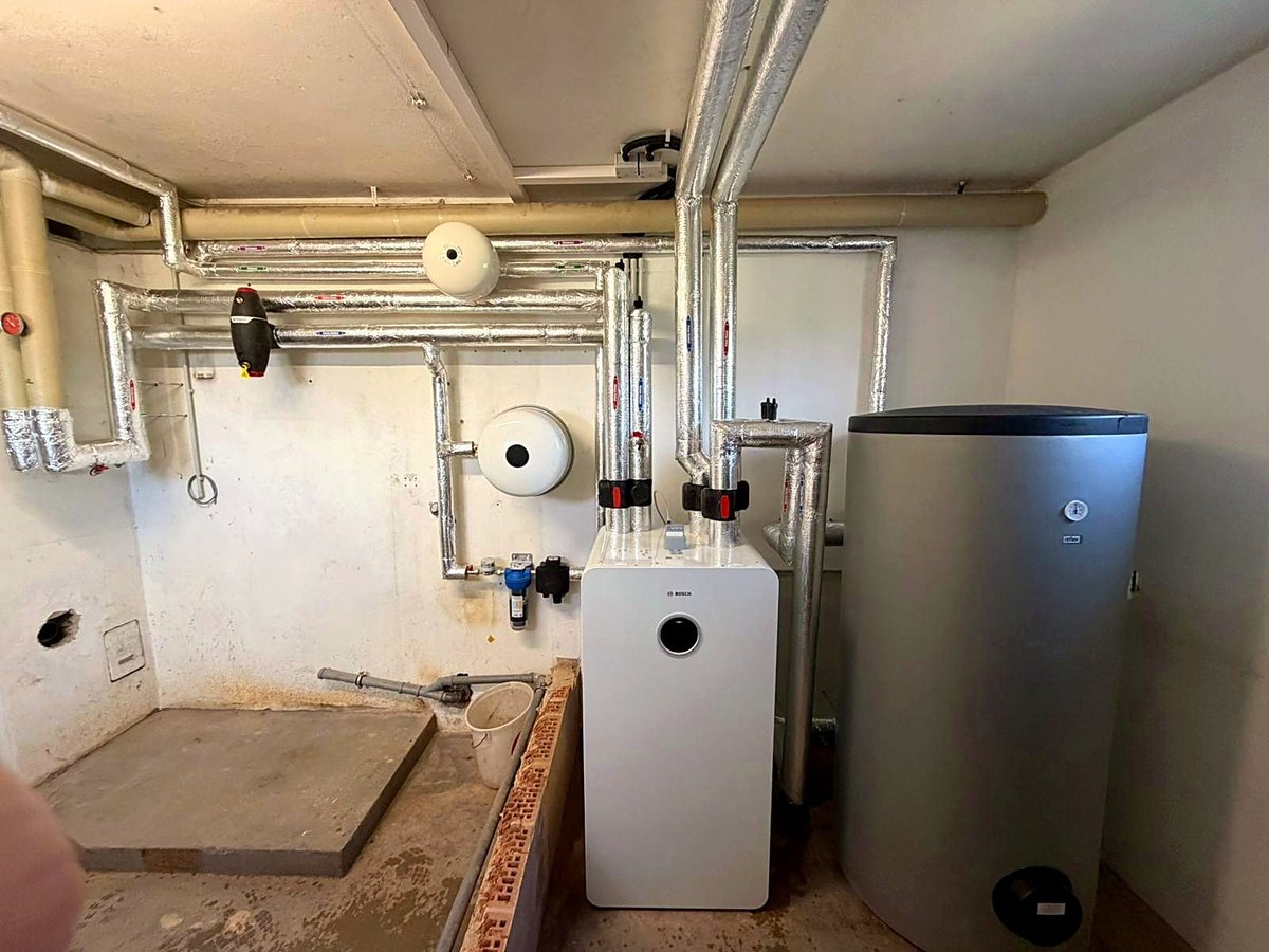 Technikraum mit Wandgerät, Pufferspeicher und gedämmten Leitungen