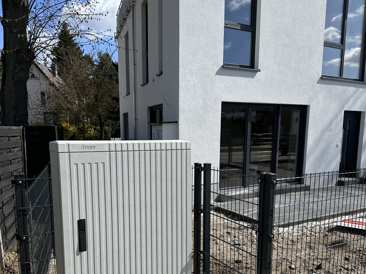 Geschlossener Anschlussschrank vor einem fertig verputzten Neubau