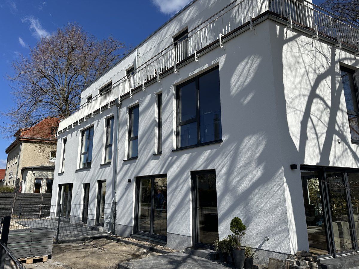 Fertig verputzte Fassade eines Mehrfamilienhauses mit Fenstern und Balkonen