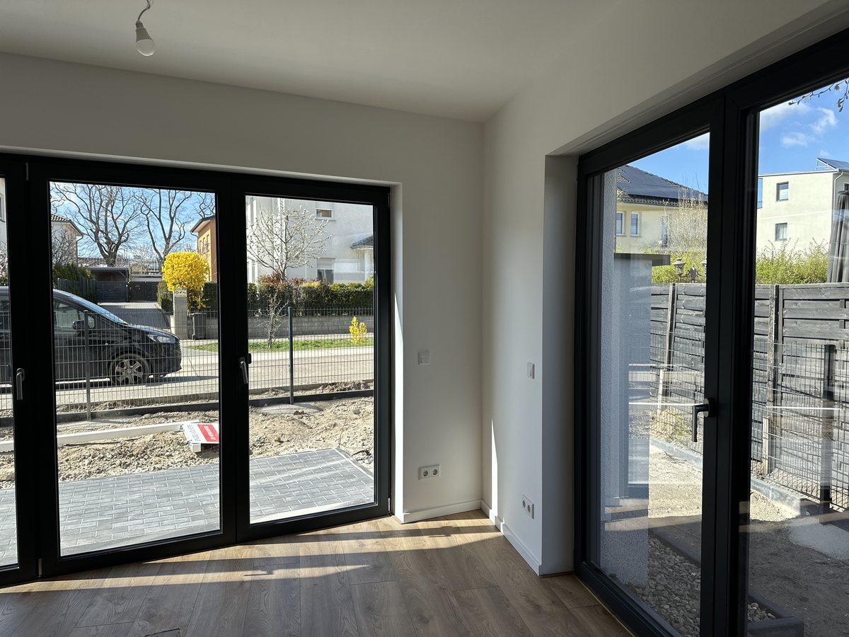 Fertiger Wohnraum mit bodentiefer Fensterfront und Balkonzugang