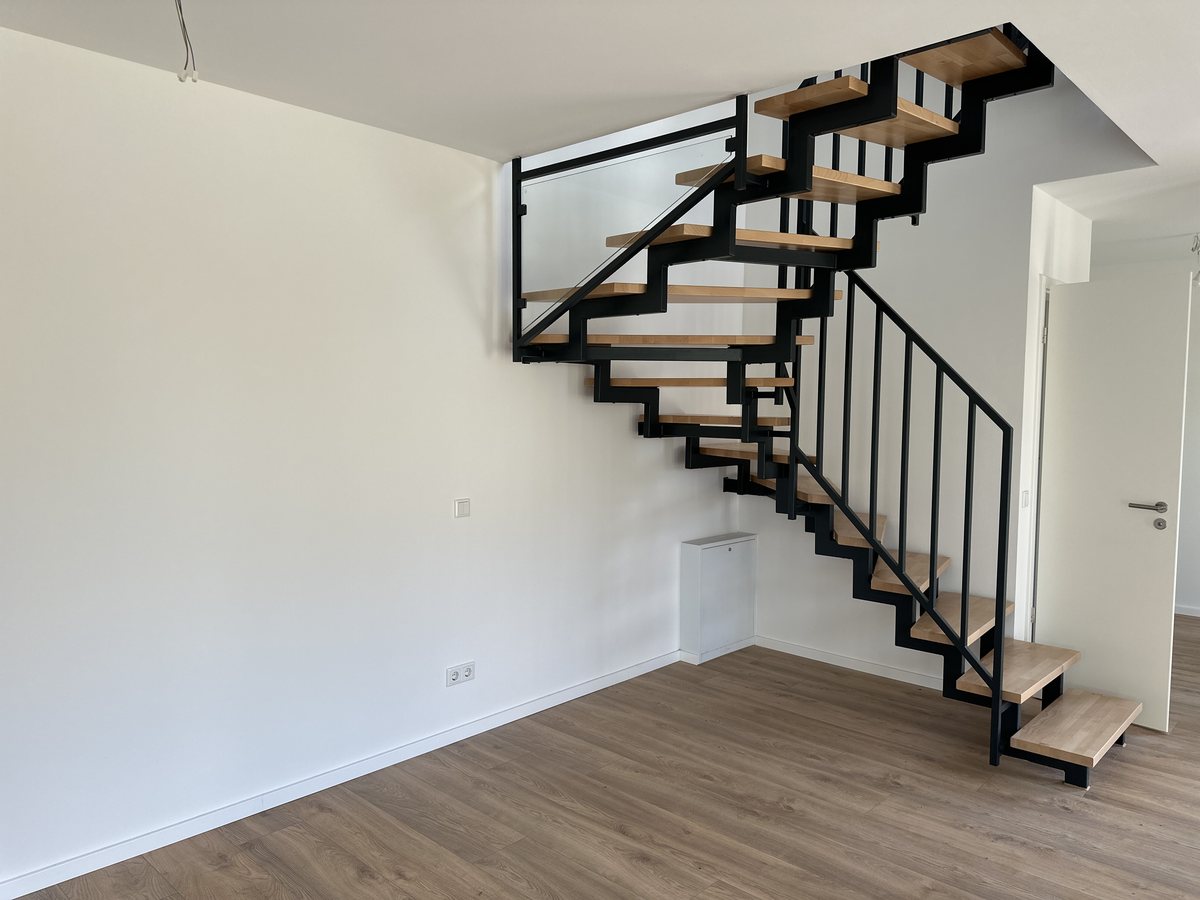 Fertige Stahltreppe mit Holzstufen und schwarzem Geländer in einem bezugsfertigen Wohnraum