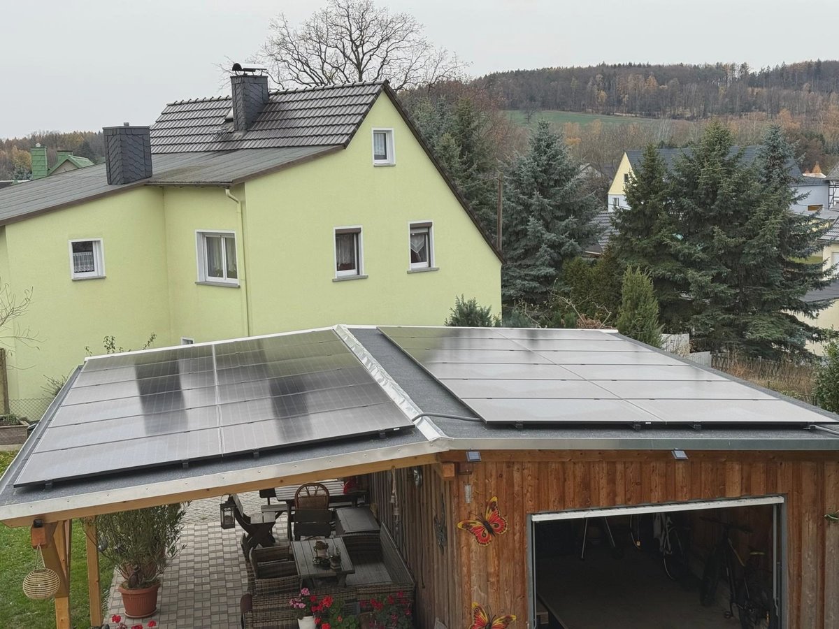 Zwei Modulfelder auf einem Carport-Dach neben dem Wohnhaus