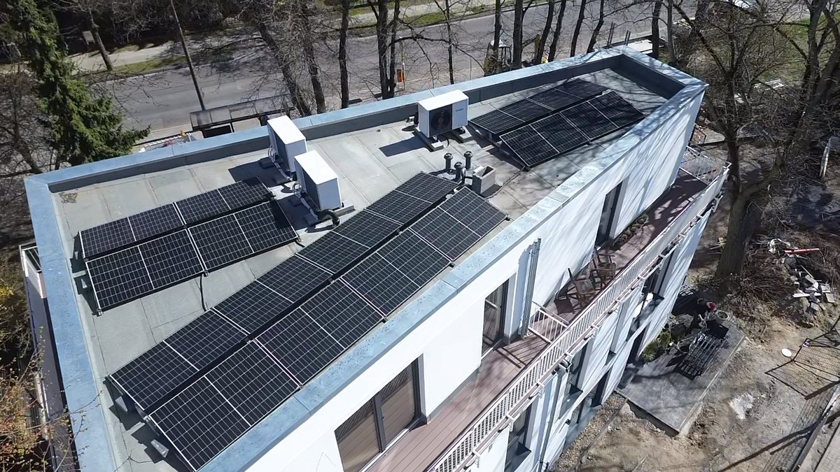 Luftaufnahme eines Flachdachs mit aufgeständerter Photovoltaikanlage und Außengeräten