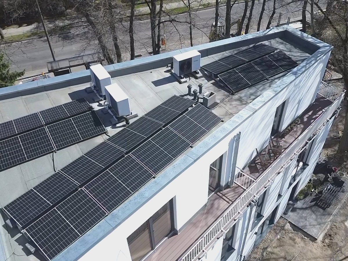 Luftaufnahme eines Flachdachs in Berlin mit Photovoltaikmodulen und drei Wärmepumpen-Außengeräten