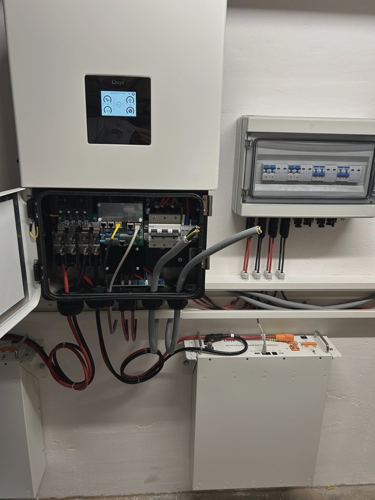 Geöffneter Wechselrichter mit Anschlussraum, daneben Batteriemodul und Reihenklemmen