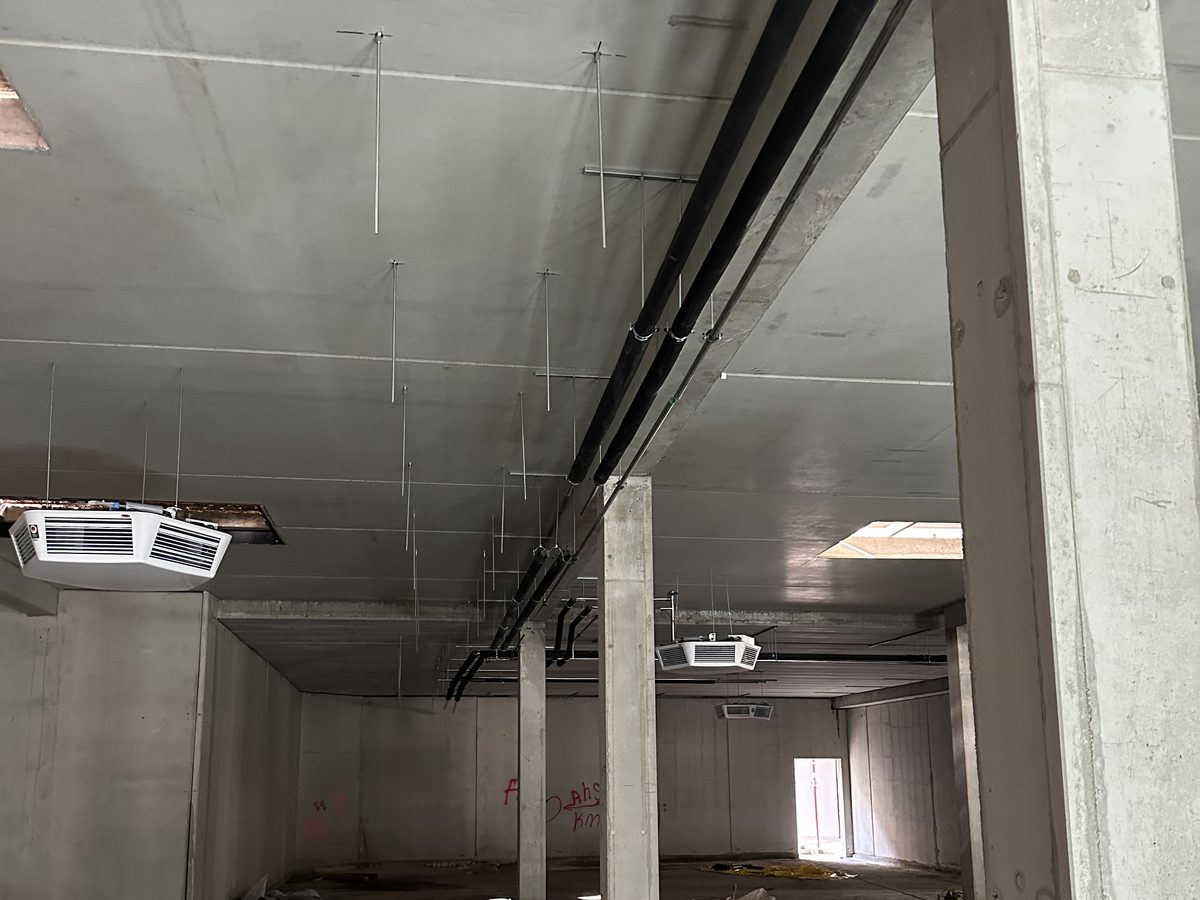 Rohbau einer Gewerbehalle mit Betonstützen, Decke und abgehängten Leitungen