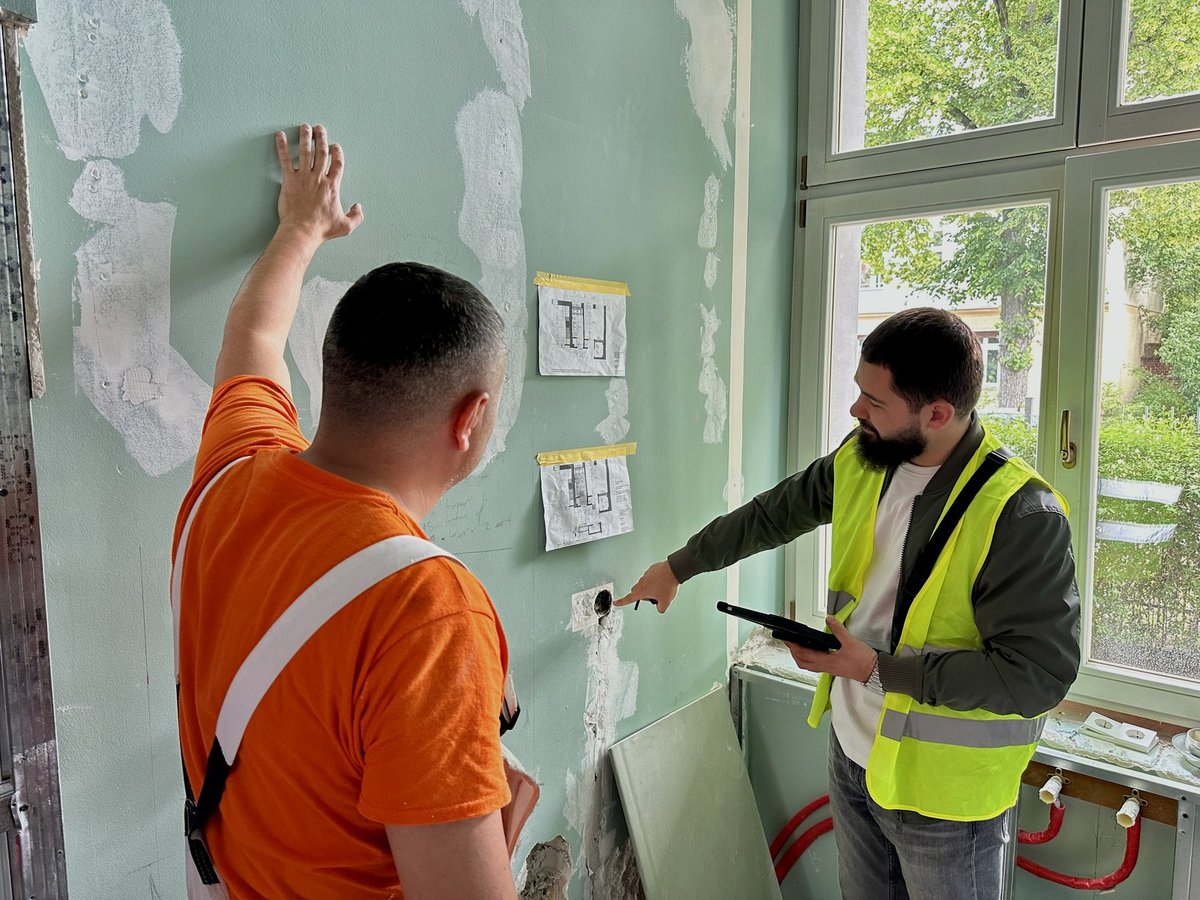 Bauleiter und Monteur stimmen vor Ort den nächsten Schritt ab, Grundrisse hängen an der Wand