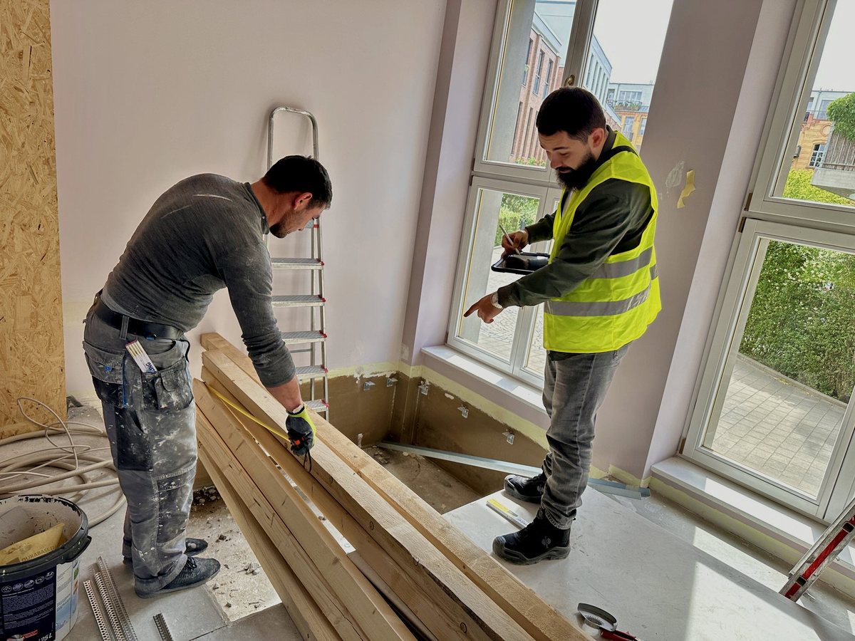 Zwei Monteure beim Aufmaß am Fenster, bevor der Boden verlegt wird