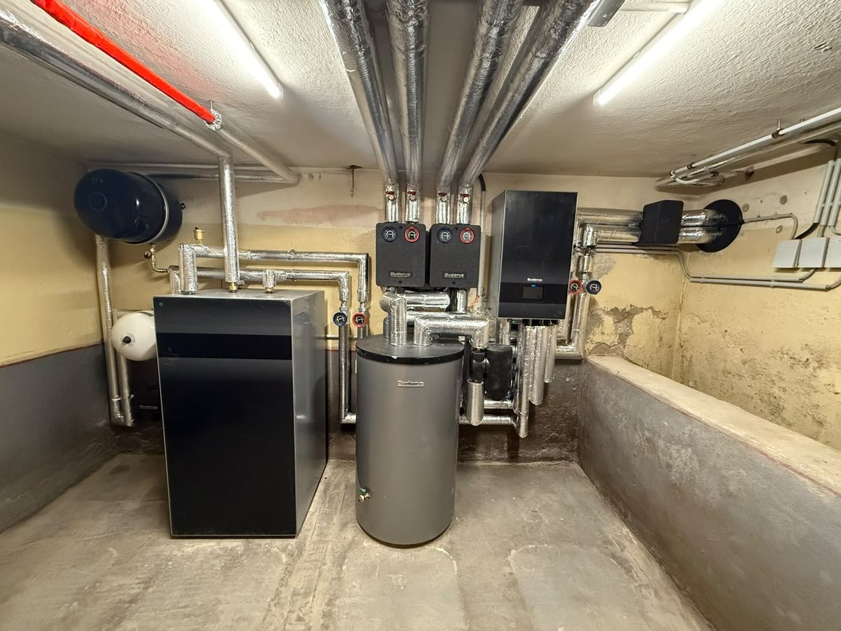 Aufgeräumter Technikraum mit Wärmepumpen-Inneneinheit, Speicher und Verteiler