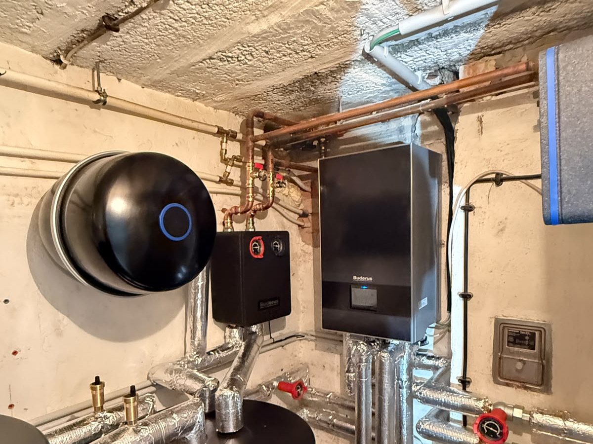 Technikraum mit Buderus-Wärmepumpen-Inneneinheit, Warmwasserspeicher und gedämmten Leitungen