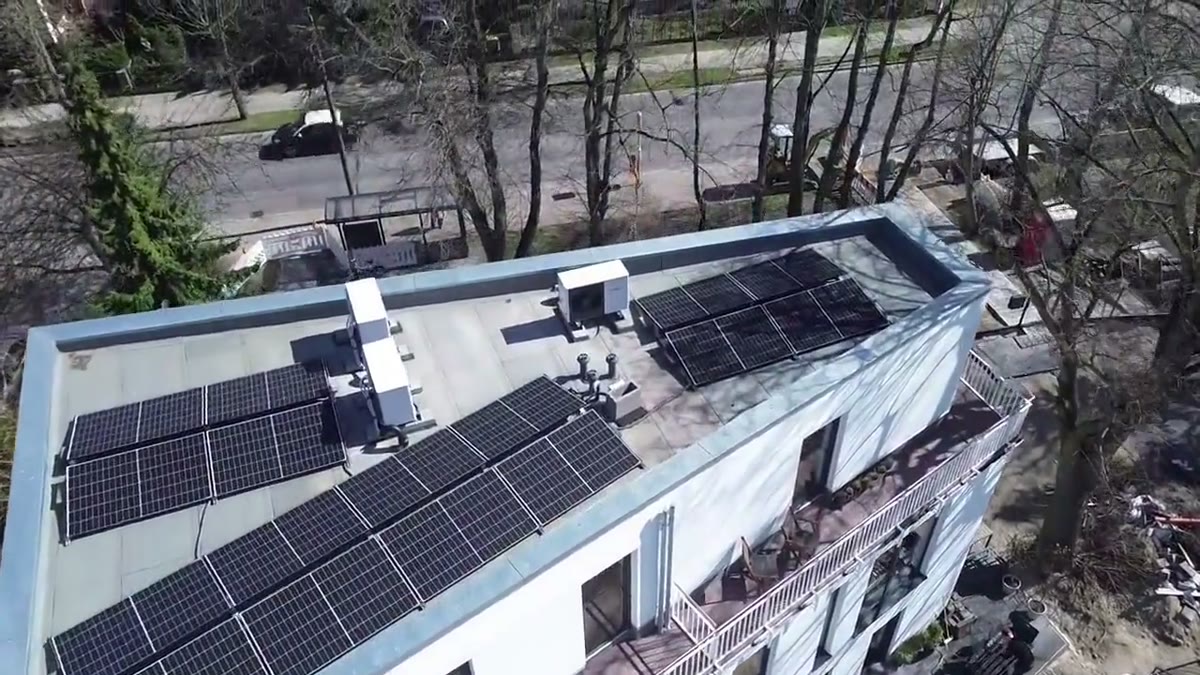 Vorschaubild: Luftaufnahme eines Flachdachs mit fertiger Photovoltaikanlage und Wärmepumpen-Außengeräten